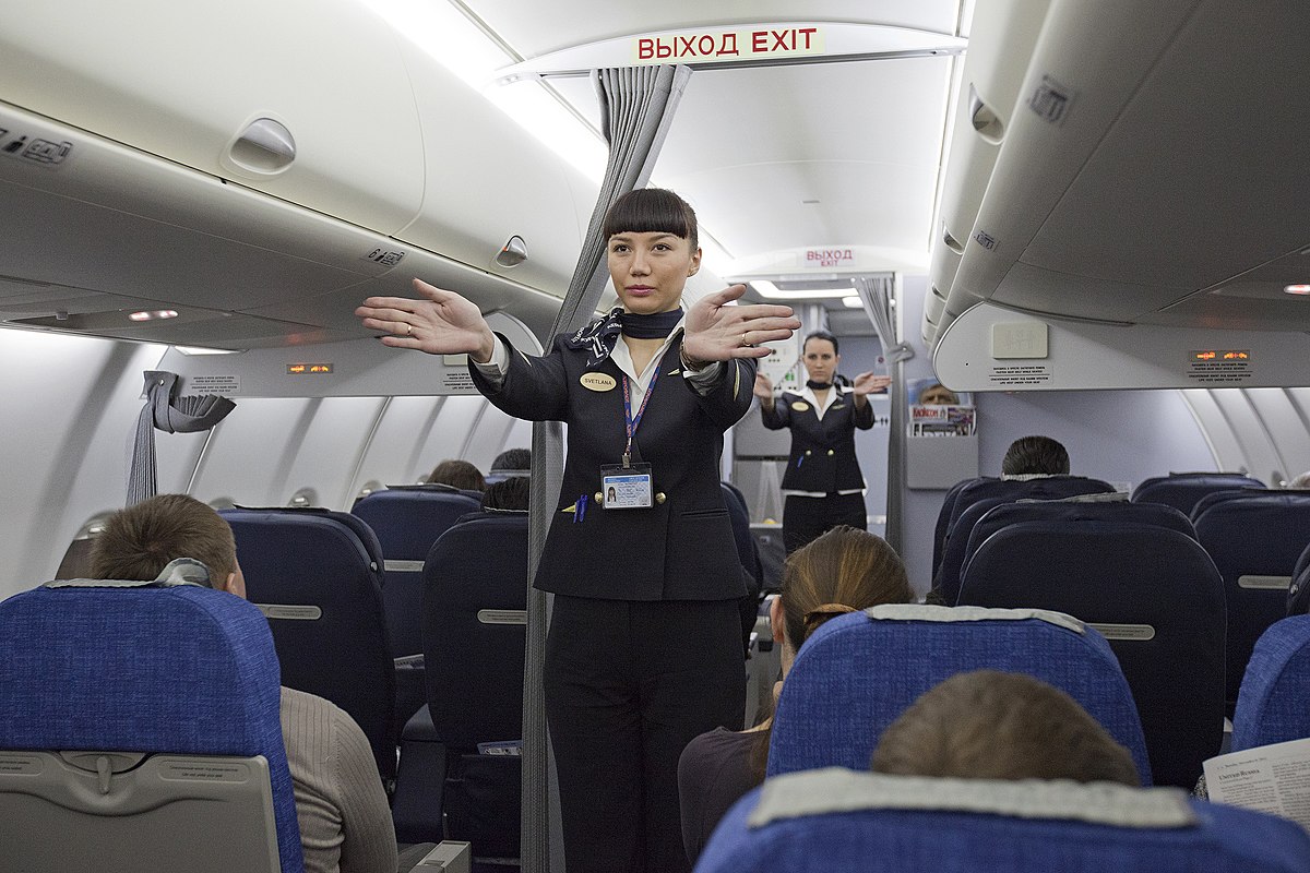 1200px-Flight_attendants_performing_a_pre-flight_safety_demonstration_on_an_Aeroflot_Sukhoi_Superjet